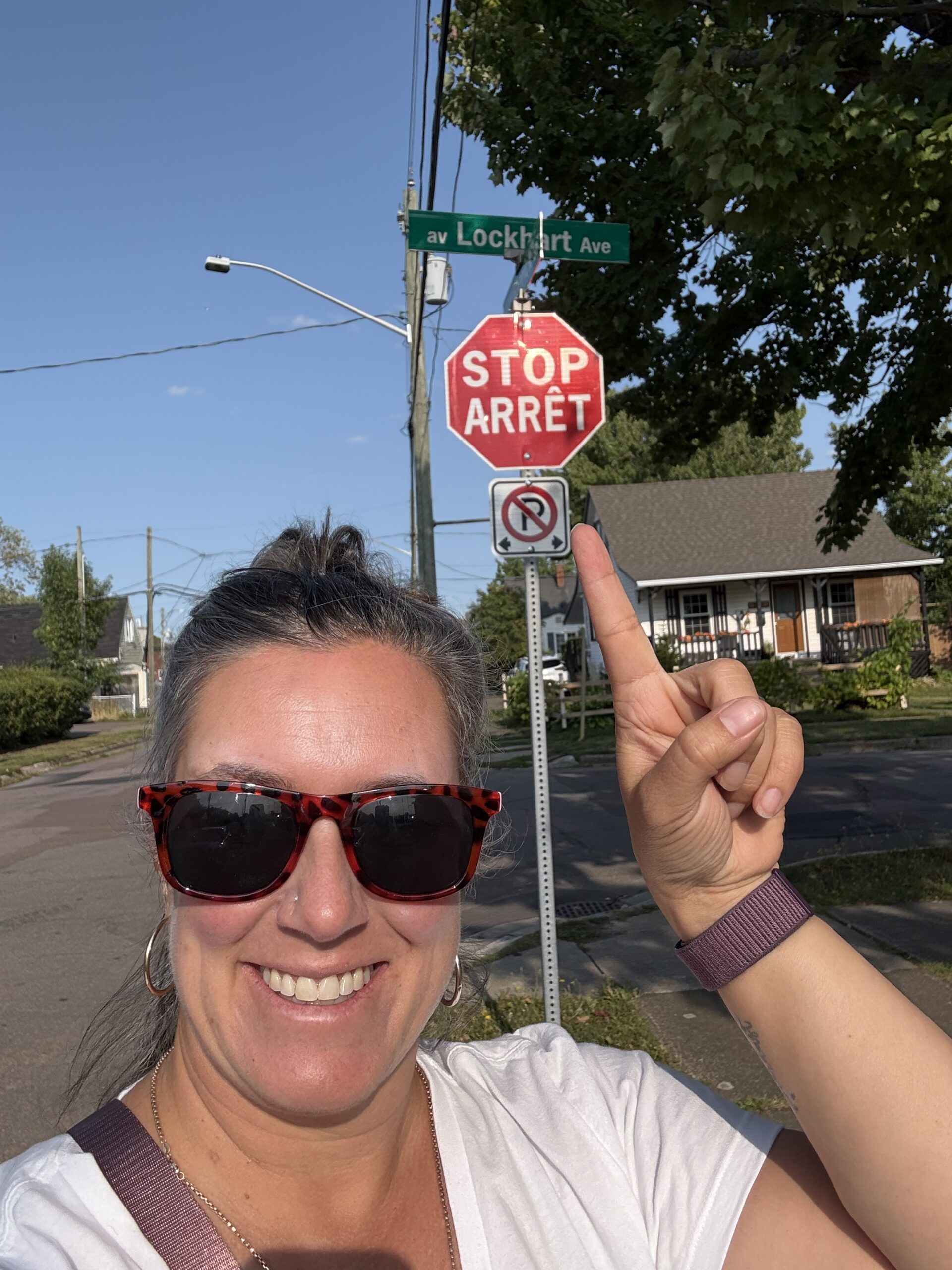 bilingual-stop-sign-maritimes Dominique pointing at a bilingual āStop / ArrĆŖtā sign in the Maritimes -highlighting the cultural connection to the Maritimes.
