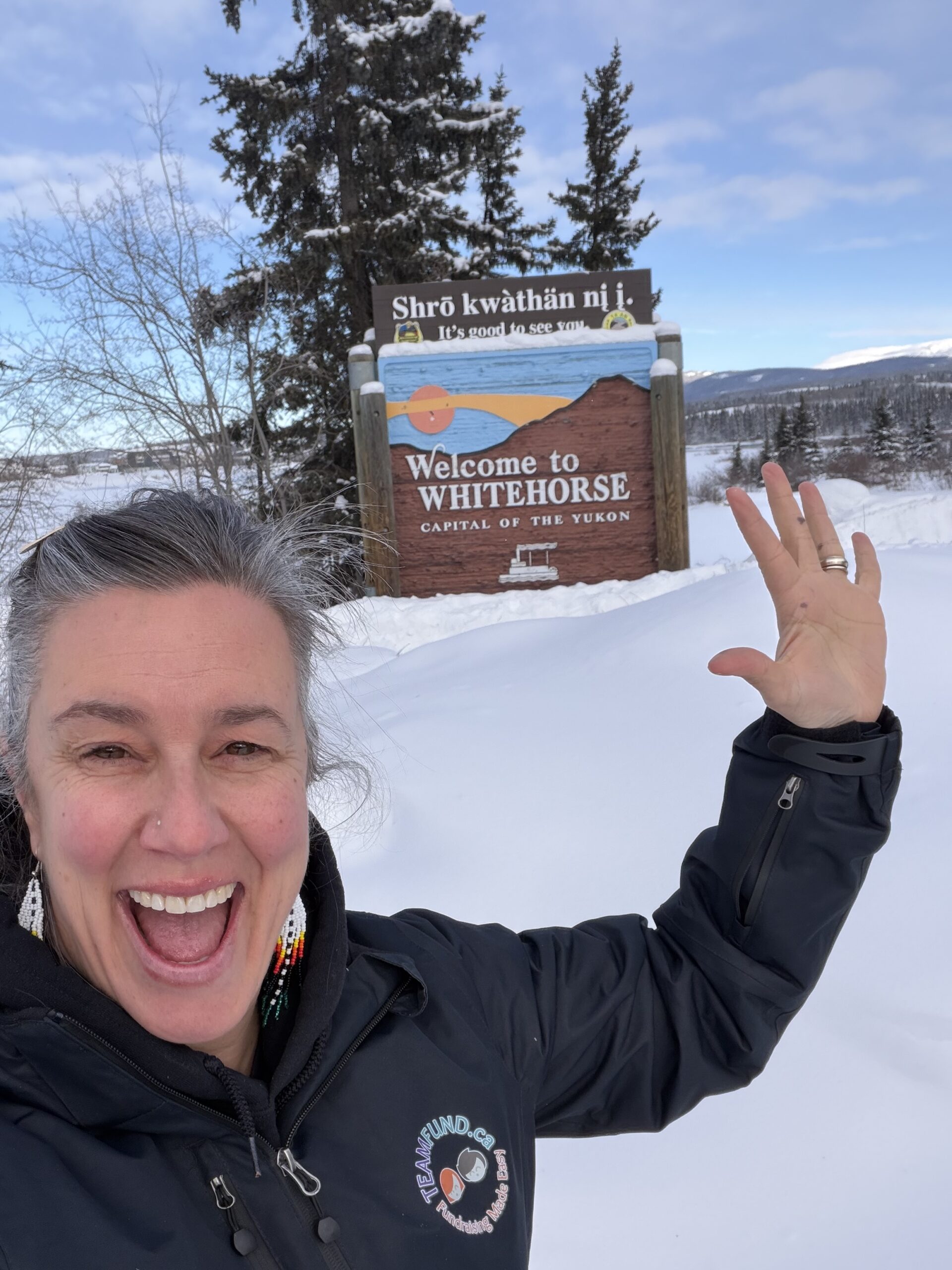Dominique from TeamFund  Fundraising standing beside the Whitehorse sign in Whitehorse, Yukon during Subzero Volleyball Club’s first fundraiser delivery.